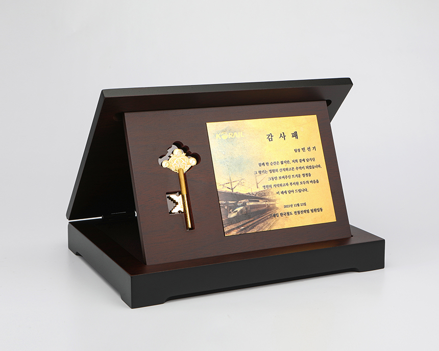 명판과 순금 열쇠가 조화롭게 배치된 기념용 상패 디자인